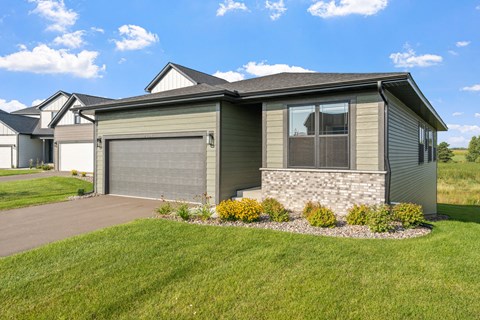 a green house with a driveway and a garage door